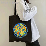 Ukrainian patriotic grocery tote bag with sunflower design, carried by a person in a gray sweater.