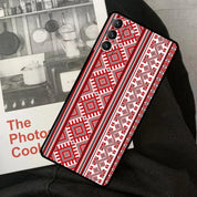 Ukrainian pattern phone case for Samsung Galaxy, featuring red and black intricate ornaments, shown on knees next to a photo book.