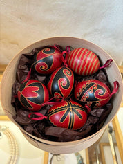 Set of 6 handmade Ukrainian Pysanky eggs with traditional red and black folk designs, displayed in a decorative box.