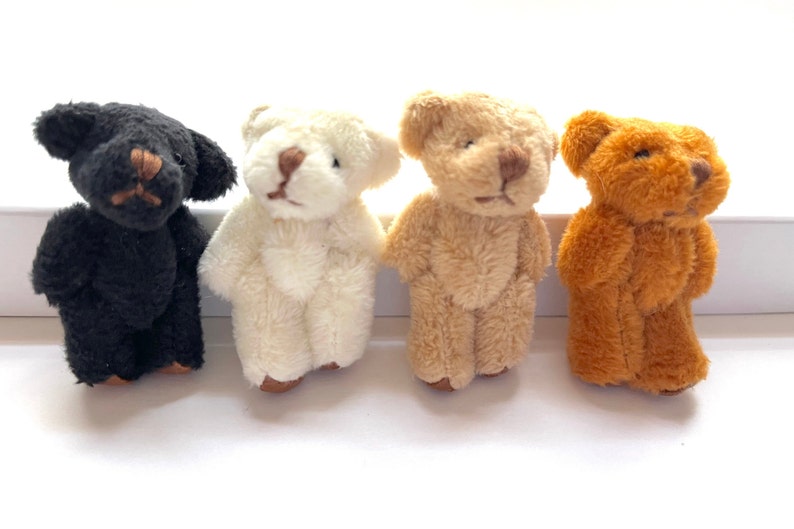 Four miniature stuffed teddy bears in different colors with moveable arms and legs, displayed in a row on a white background.
