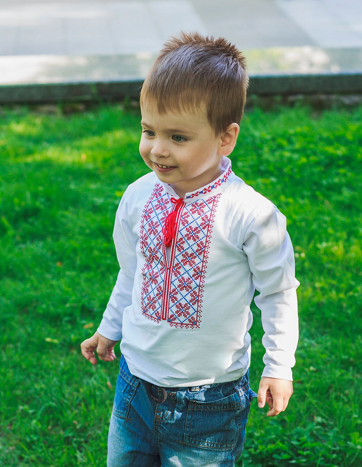 Toddler boy wearing traditional Ukrainian embroidered vyshyvanka shirt outdoors.