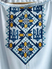 Close-up of embroidered Ukrainian Vyshyvanka dress featuring blue and yellow Trident and floral patterns.