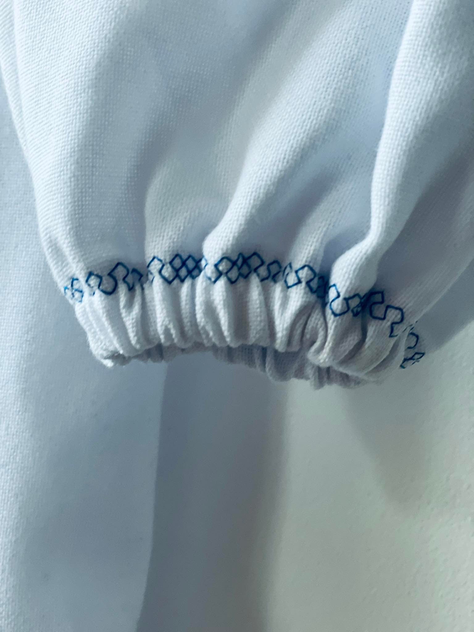 Close-up of blue cross-stitch embroidery on white Vyshyvanka dress sleeve, showcasing traditional Ukrainian design.