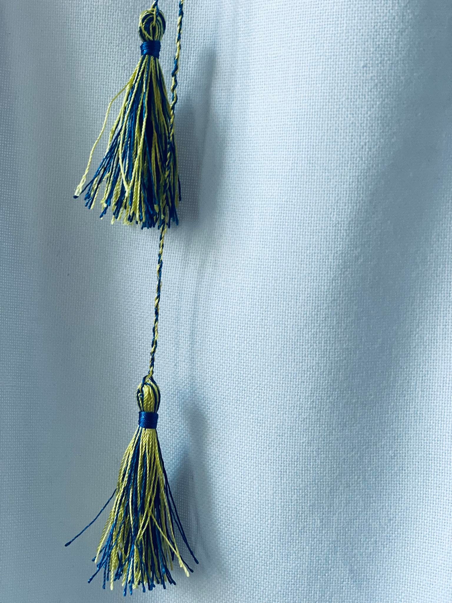 Close-up of blue and yellow tassels on Ukrainian Vyshyvanka dress for girls.