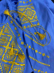 Vibrant blue and gold embroidered blouse, boho Ukrainian vyshyvanka style with tassels, showcasing intricate folk art patterns.