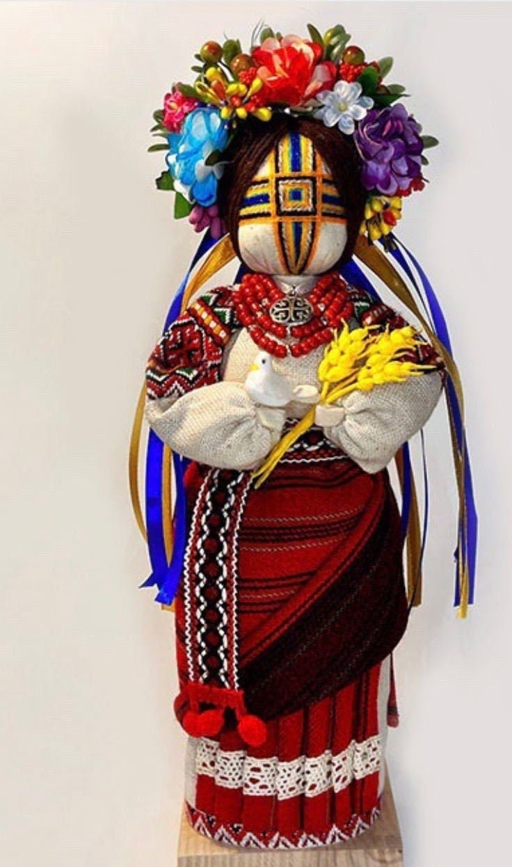 Handmade Ukrainian Motanka Doll "Invincible" with dove and wheat, symbolizing strength, peace, and protection, on a wooden stand.