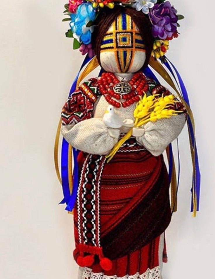 Handmade Ukrainian Motanka Doll "Invincible" with dove and wheat, symbolizing strength, peace, and protection, on a wooden stand.