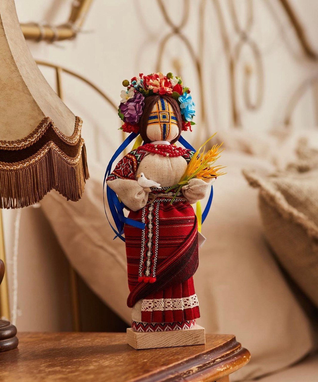 Handmade Ukrainian Motanka Doll "Invincible" with dove and wheat on wooden stand, symbolizing strength and peace.
