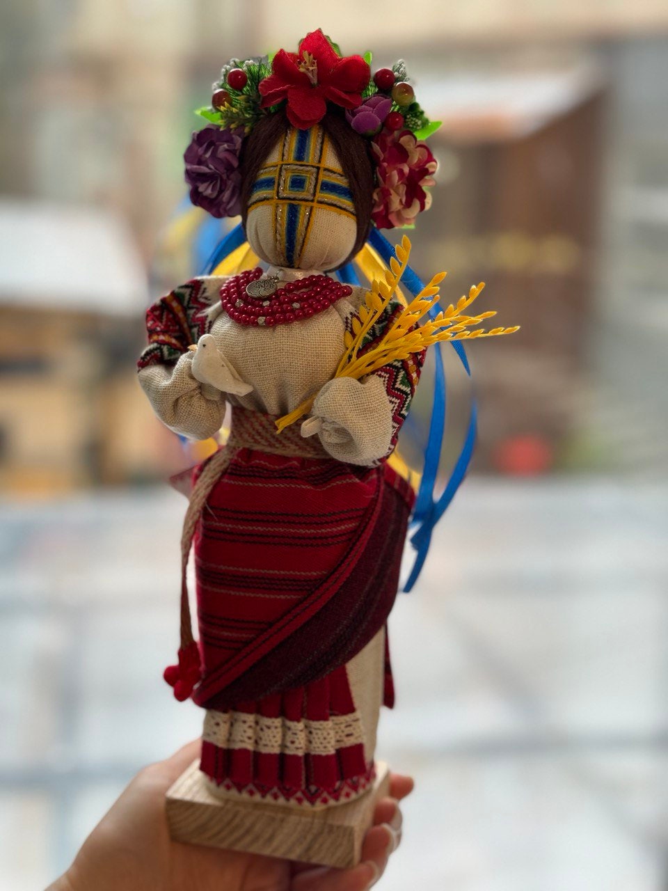 Handmade Ukrainian Motanka Doll "Invincible" with dove and wheat, symbolizing strength and peace, on a wooden stand.