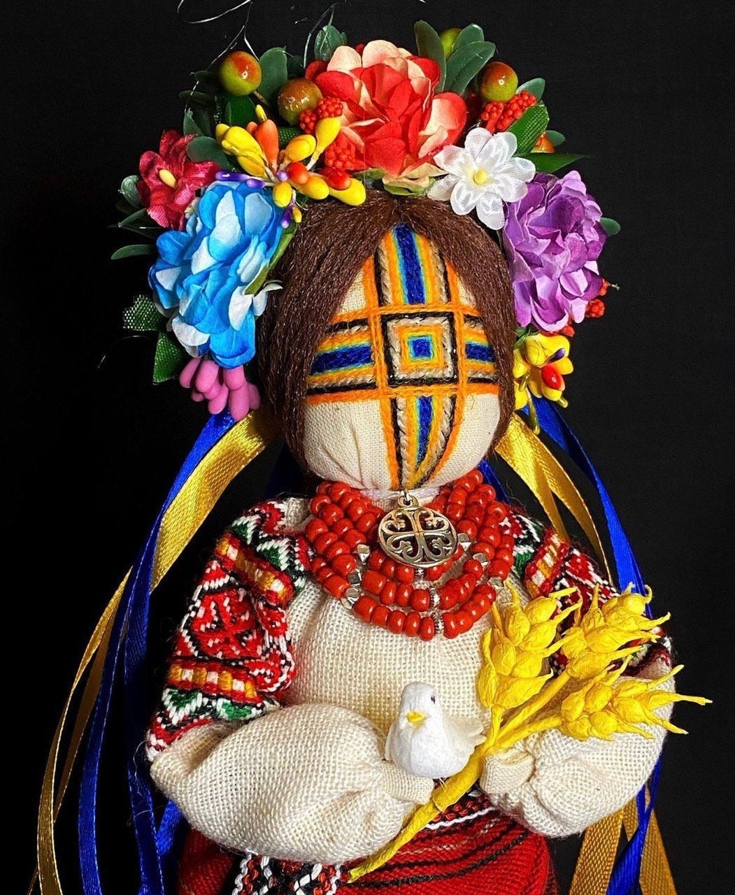Handmade Ukrainian Motanka Doll "Invincible" with colorful floral headdress, holding a dove and wheat, symbolizing strength and peace.