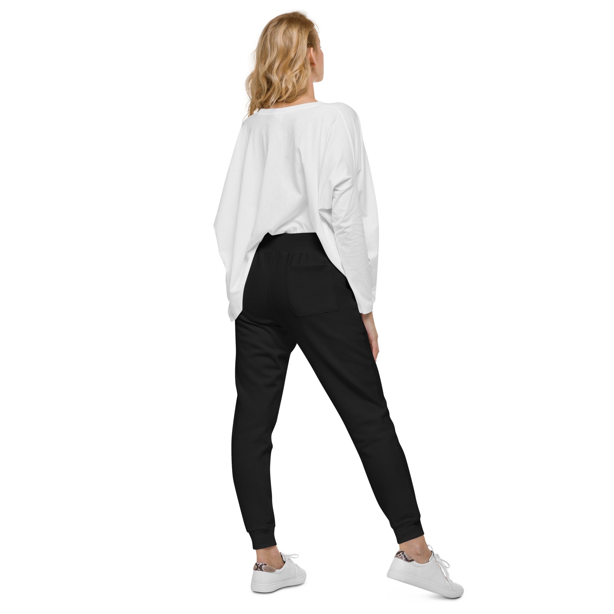 Back view of model wearing Ukrainian Vibe Trizub Unisex Fleece Sweatpants with white sneakers and a loose white top.