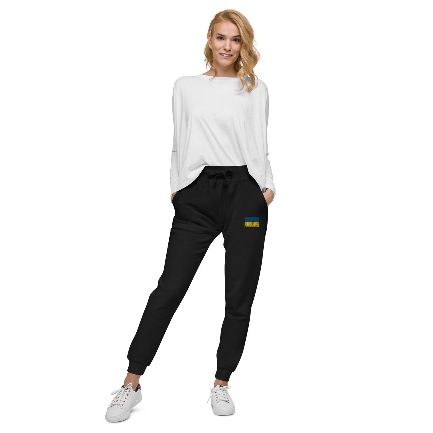 Woman wearing Ukrainian Flag fleece sweatpants and white top, showcasing casual style and comfort from the Ukrainian Vibe Trizub Collection.