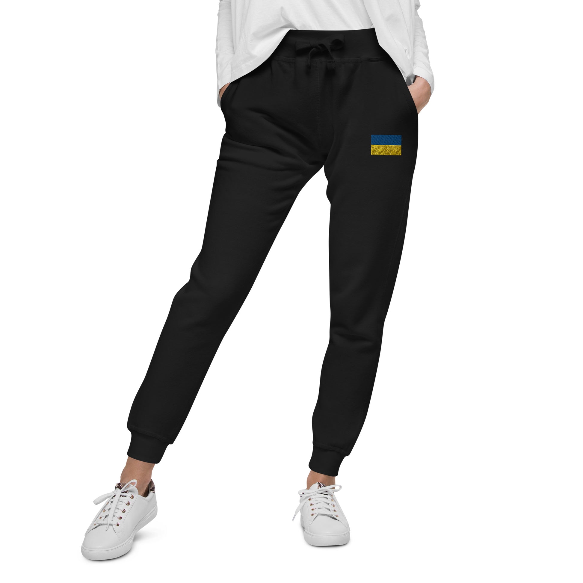 Woman wearing Ukrainian Flag fleece sweatpants from Ukrainian Vibe Trizub Collection, paired with white sneakers for casual look.