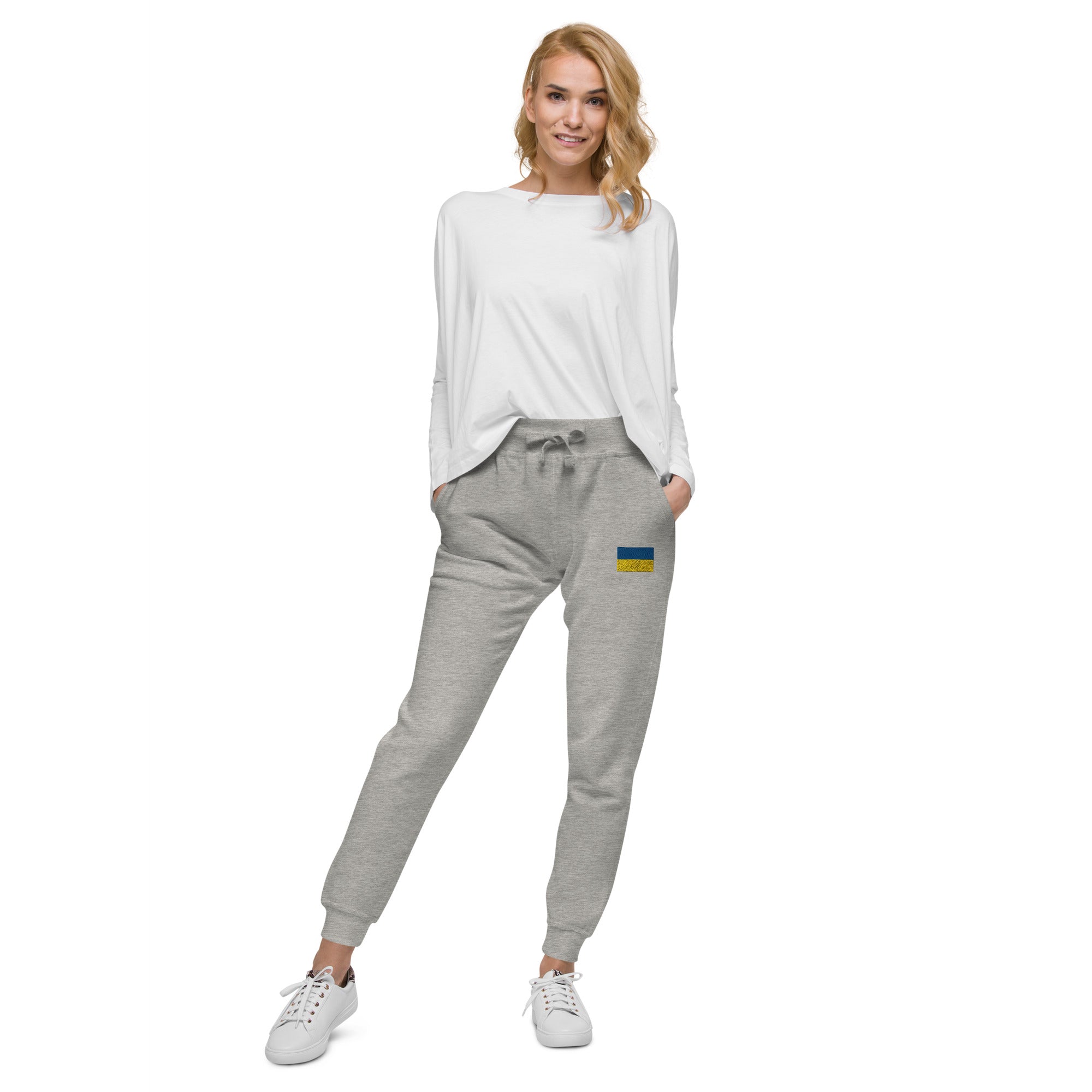 Woman wearing Ukrainian Flag fleece sweatpants from the Ukrainian Vibe Trizub Collection, paired with a white top and sneakers.