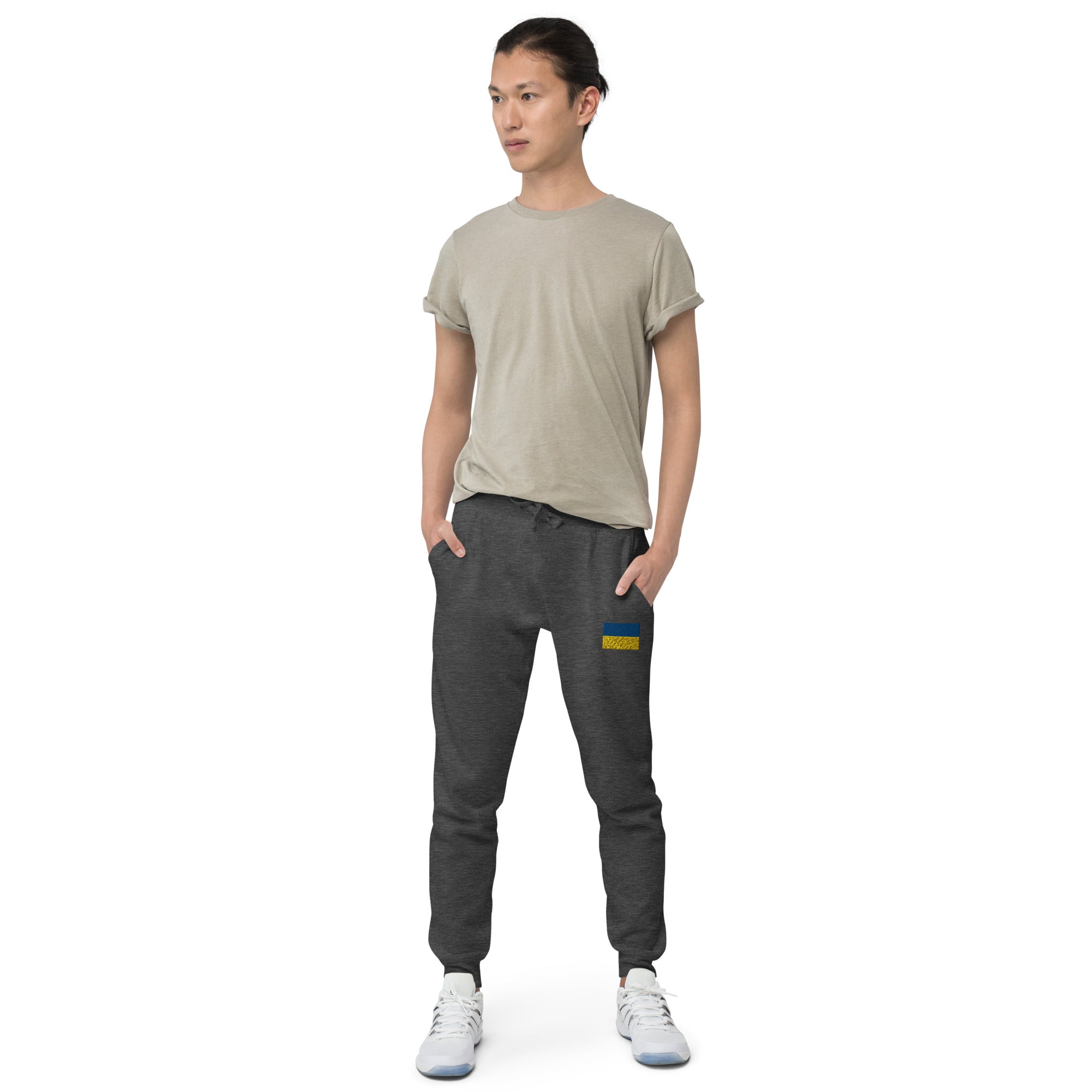 Person wearing Ukrainian Flag fleece sweatpants in dark gray with a casual tee and sneakers, showcasing a stylish unisex design.