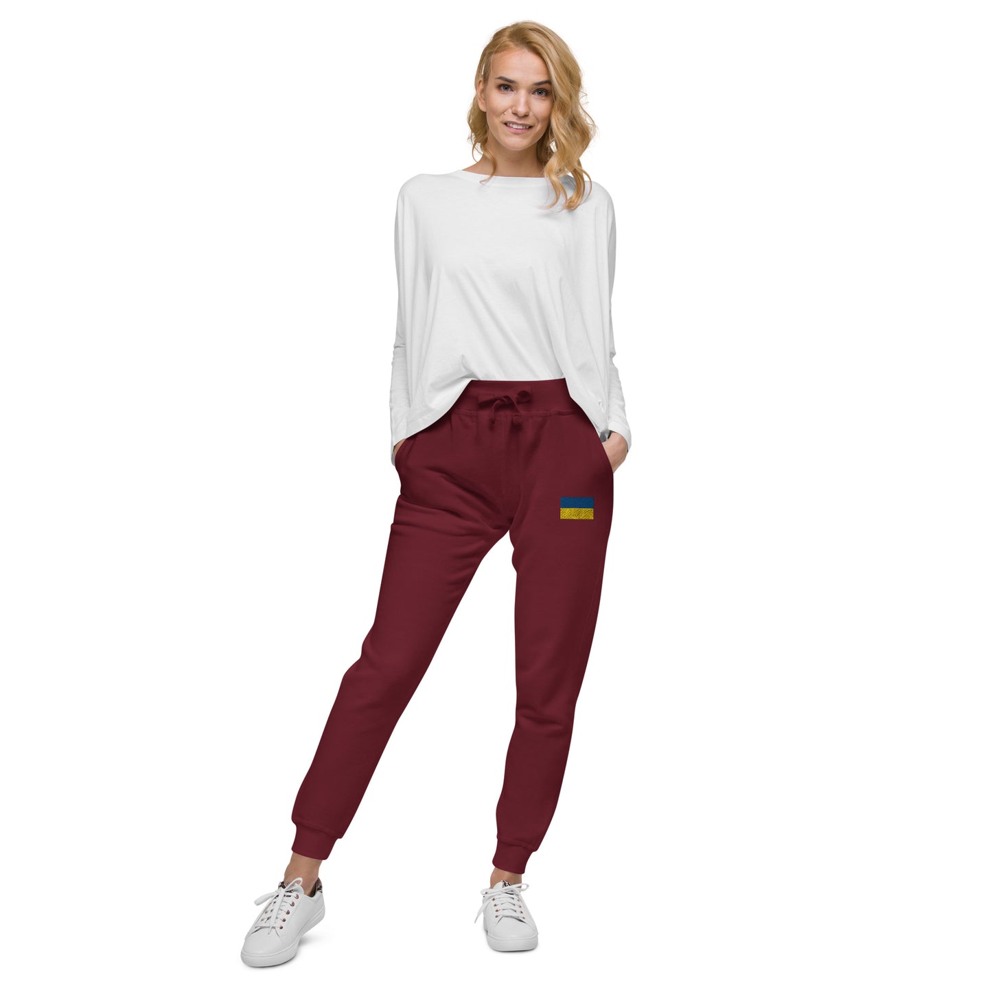 Woman wearing Ukrainian Flag fleece sweatpants in burgundy with a comfy white top and sneakers.