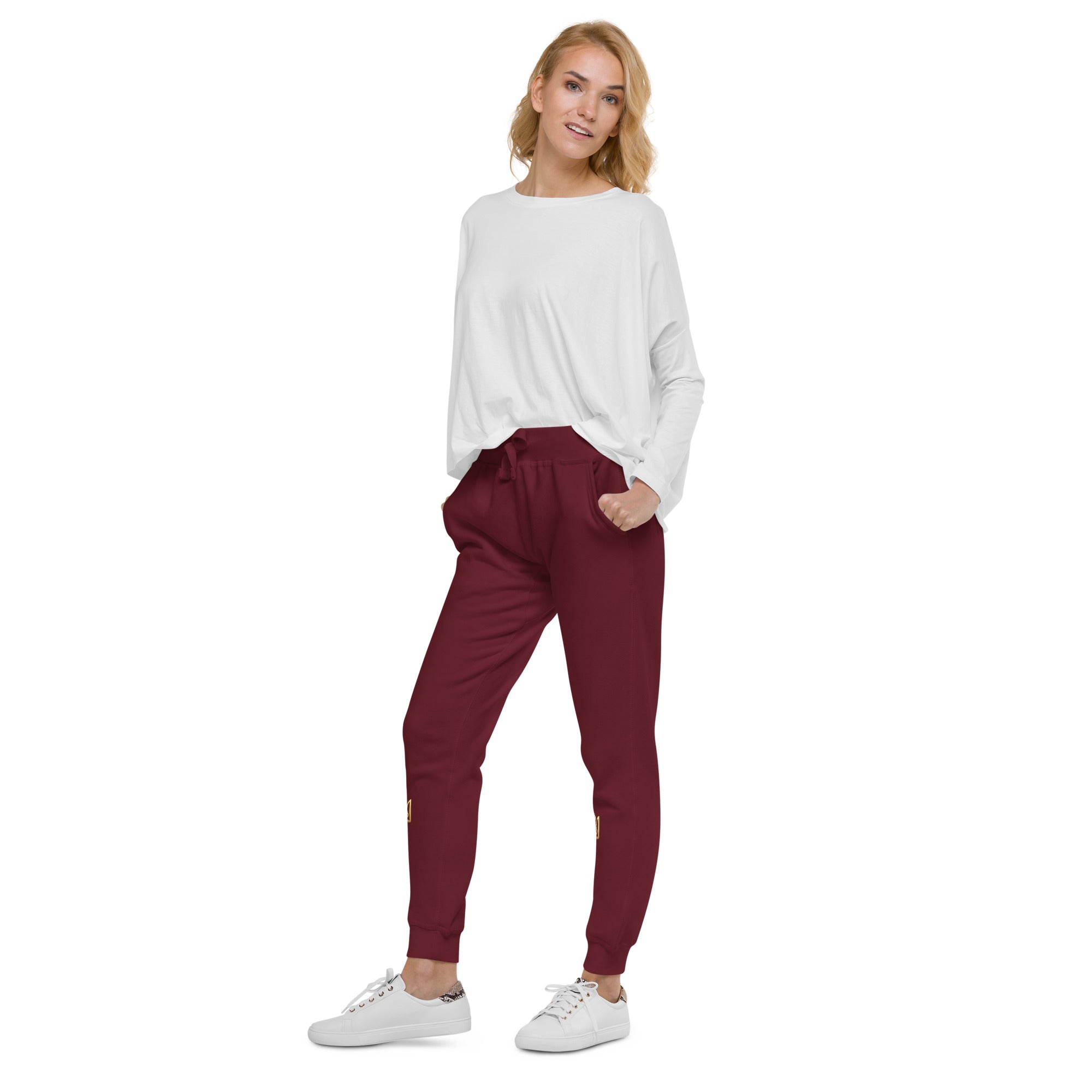 Woman wearing Ukrainian Vibe Trizub unisex fleece sweatpants in burgundy, paired with a white top and sneakers.