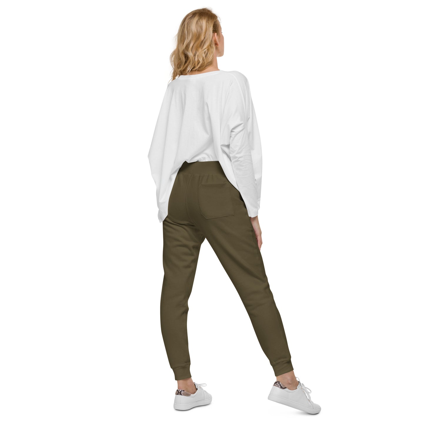 Woman wearing olive green sweatpants with white sneakers and a white top, showcasing a casual back view.