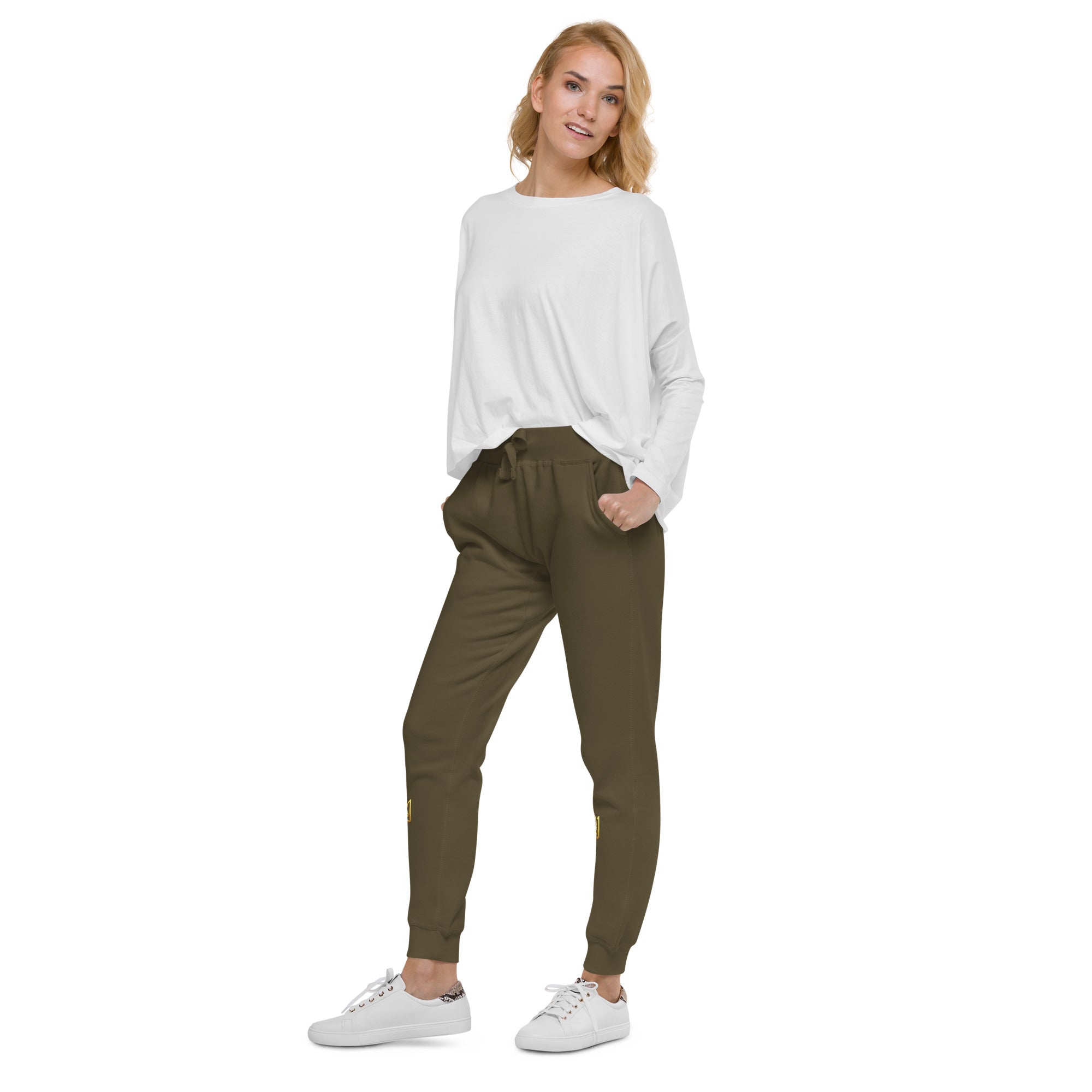 Model wearing Ukrainian Vibe Trizub fleece sweatpants in olive green paired with a white top and sneakers, showcasing casual style.