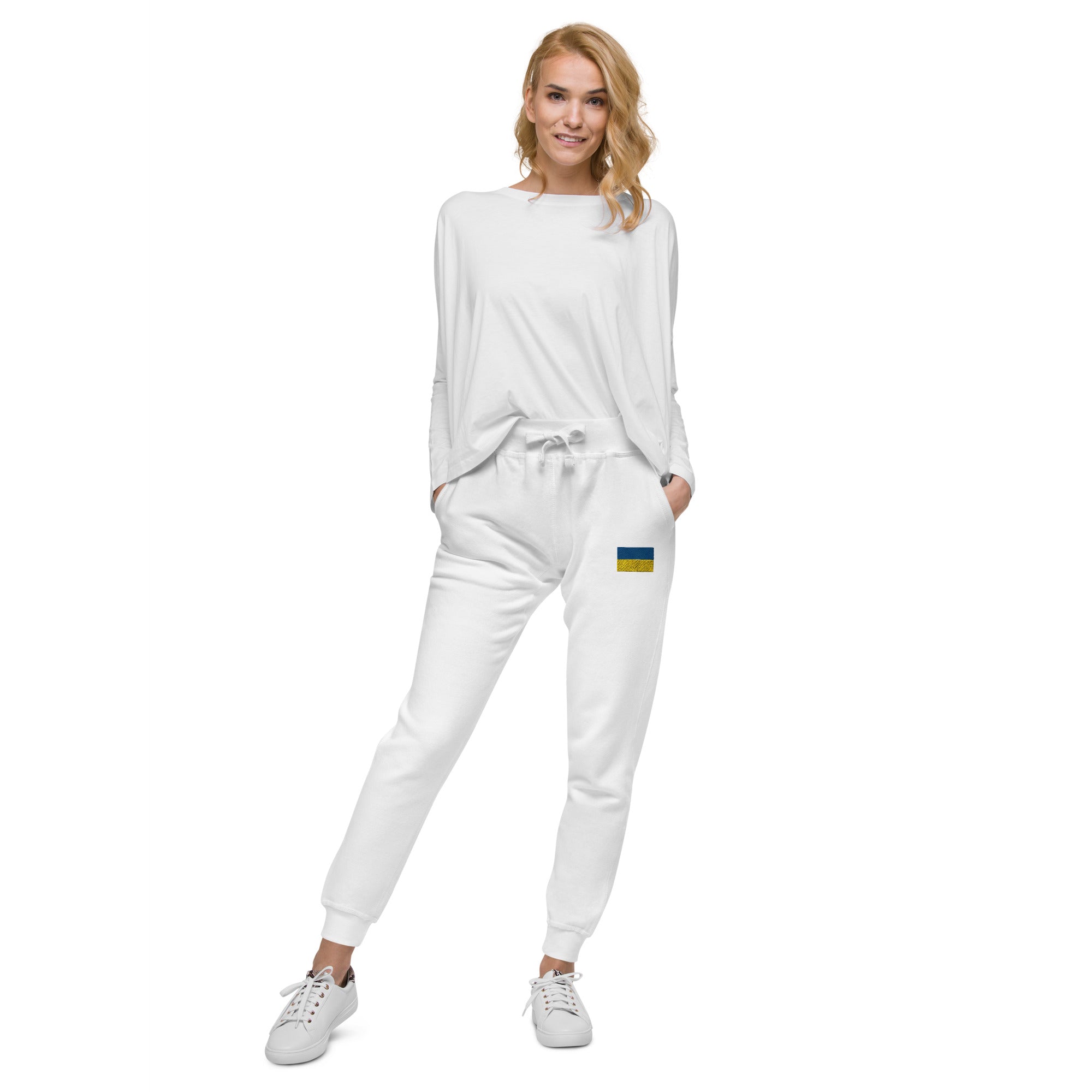 Woman wearing white Ukrainian Flag fleece sweatpants with a casual top and sneakers.