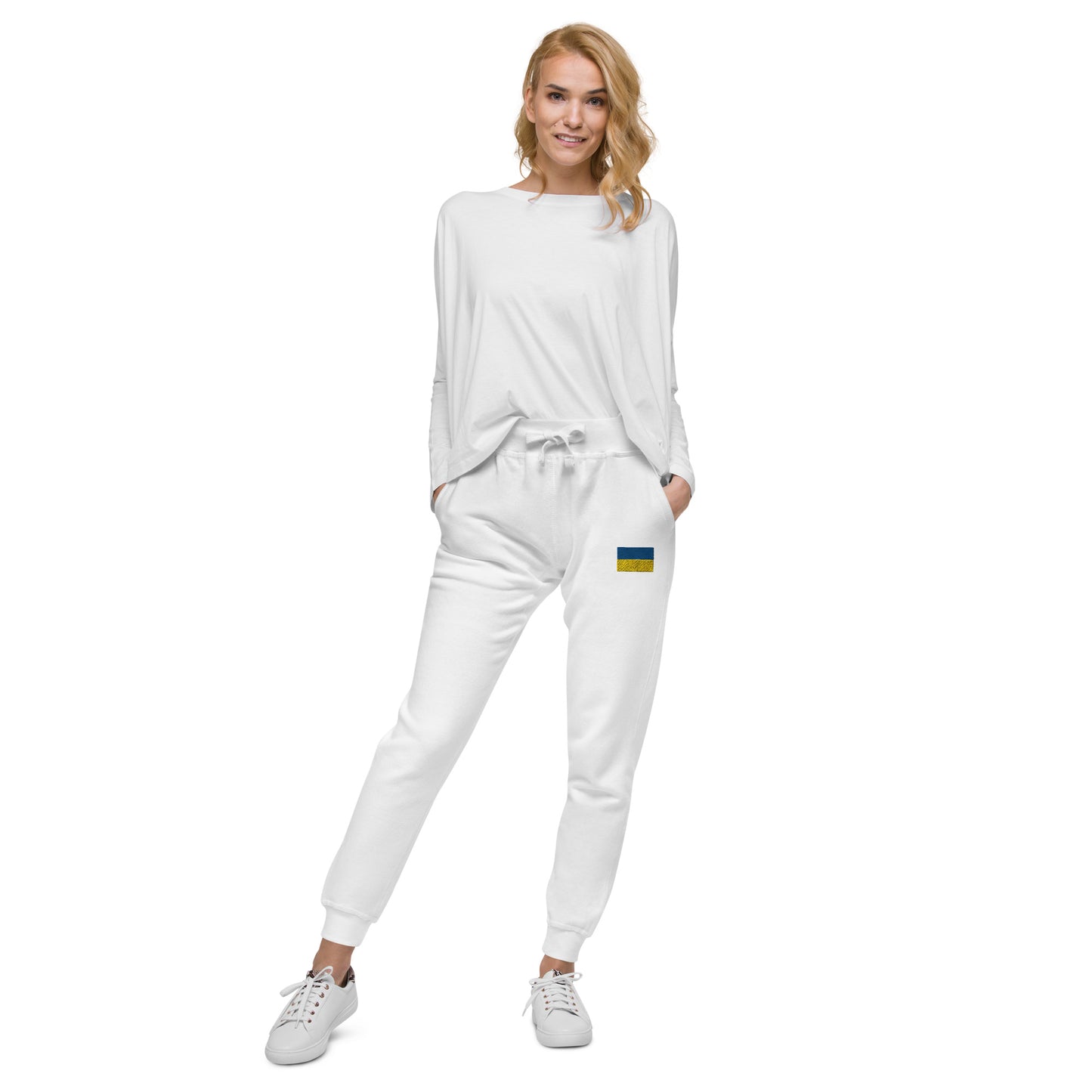 Woman wearing white Ukrainian Flag fleece sweatpants with a casual top and sneakers.