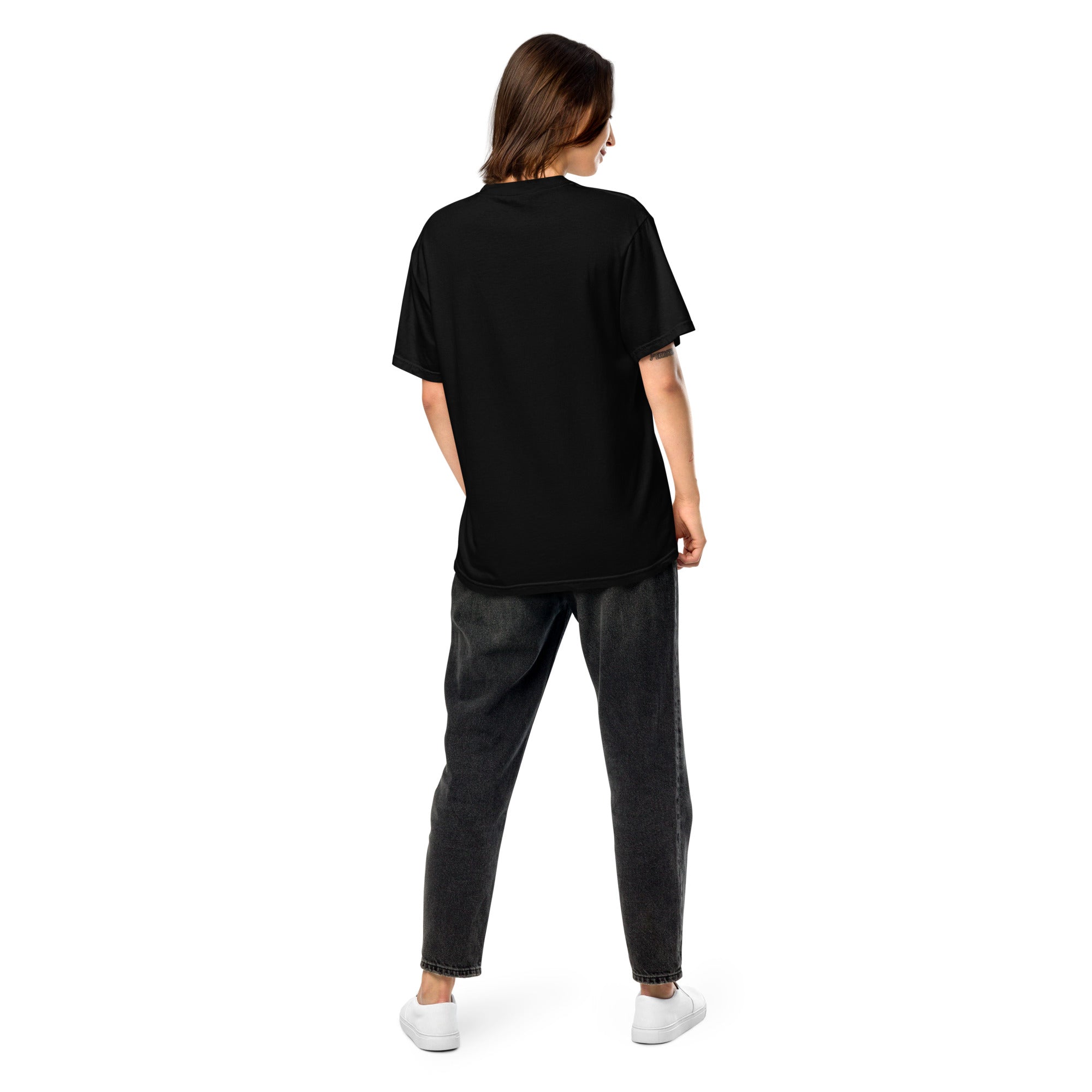Back of model wearing black women's garment-dyed heavyweight T-shirt from Ukrainian Vibe Trizub Collection, paired with jeans.