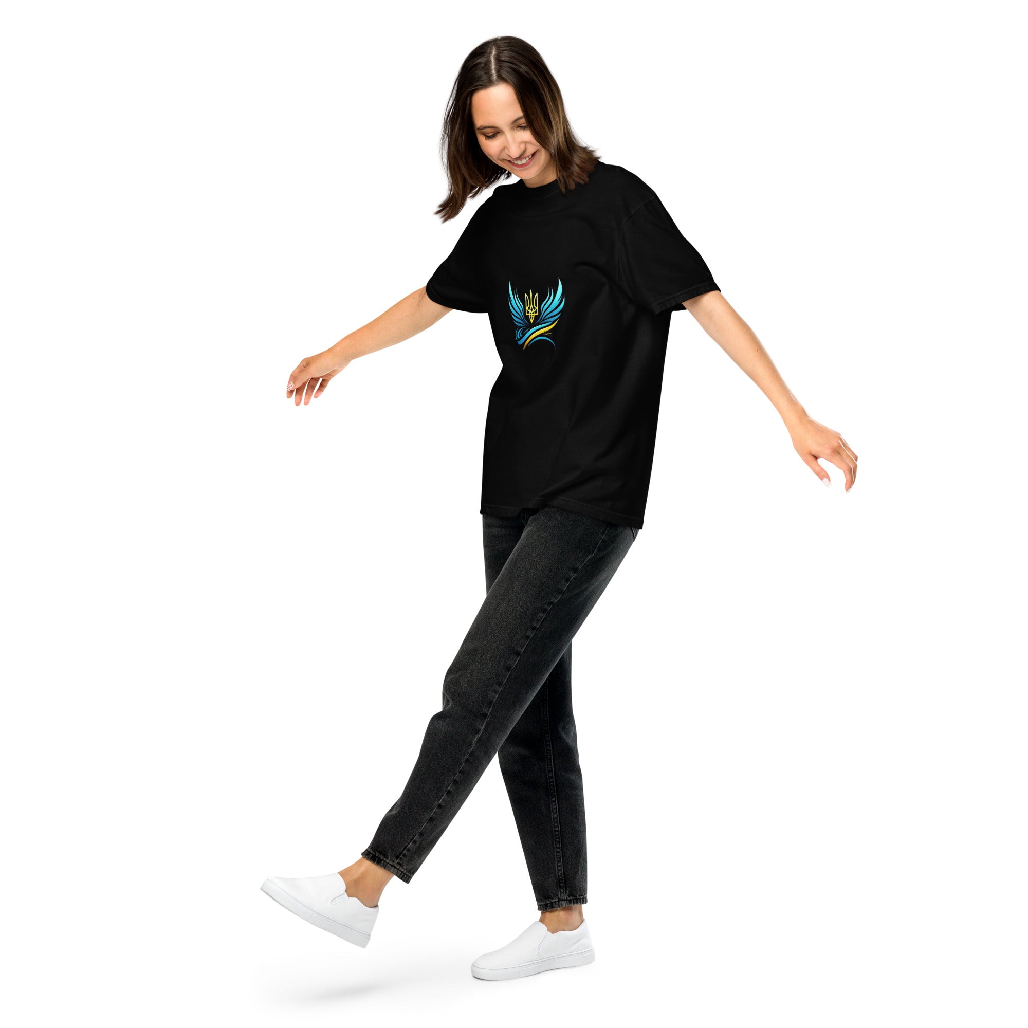 Woman in black Ukrainian Vibe Trizub Collection t-shirt with blue emblem, showing off relaxed fit and style, paired with dark jeans and white sneakers.