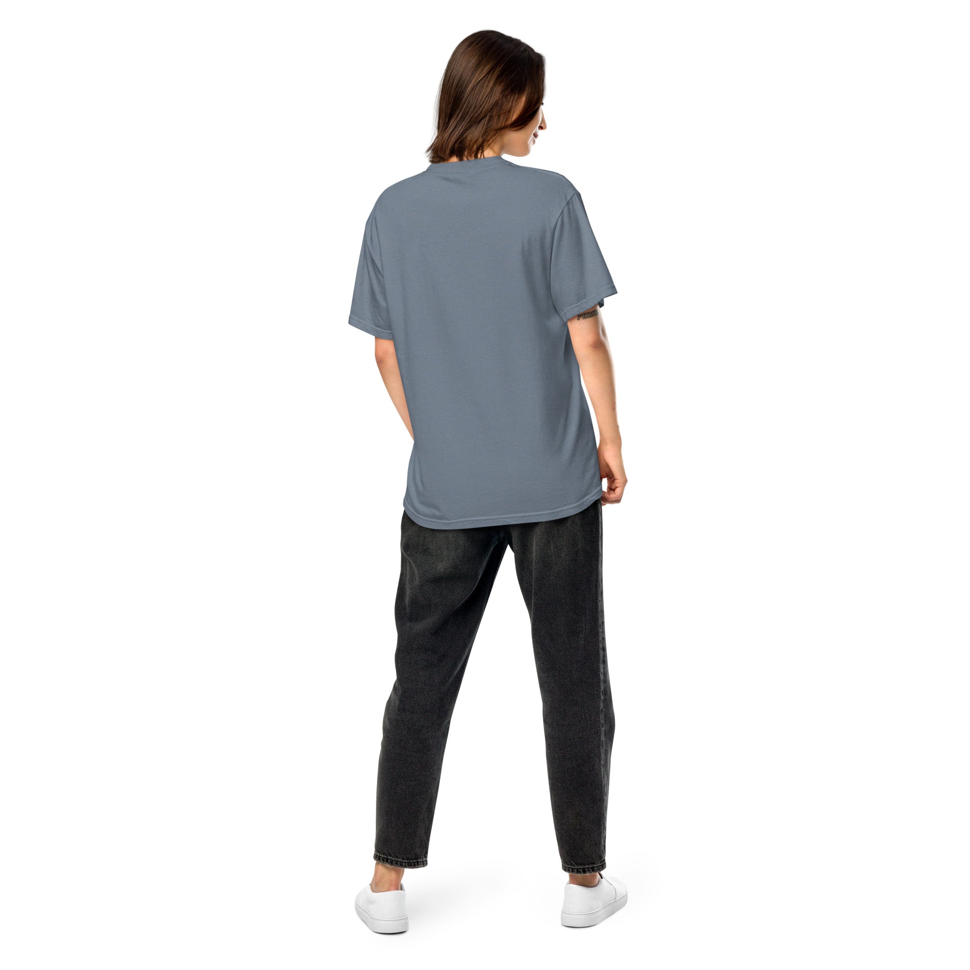 Back view of woman wearing Ukrainian Vibe Trizub Collection garment-dyed heavyweight t-shirt in grey, paired with black jeans, standing.