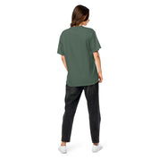 Back view of a woman wearing a green Ukrainian Vibe Trizub Collection heavyweight t-shirt and black jeans, showcasing a relaxed fit.