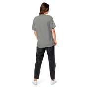 Back view of a woman wearing a Ukrainian Vibe Trizub Collection garment-dyed heavyweight t-shirt in gray, paired with black jeans and white sneakers.