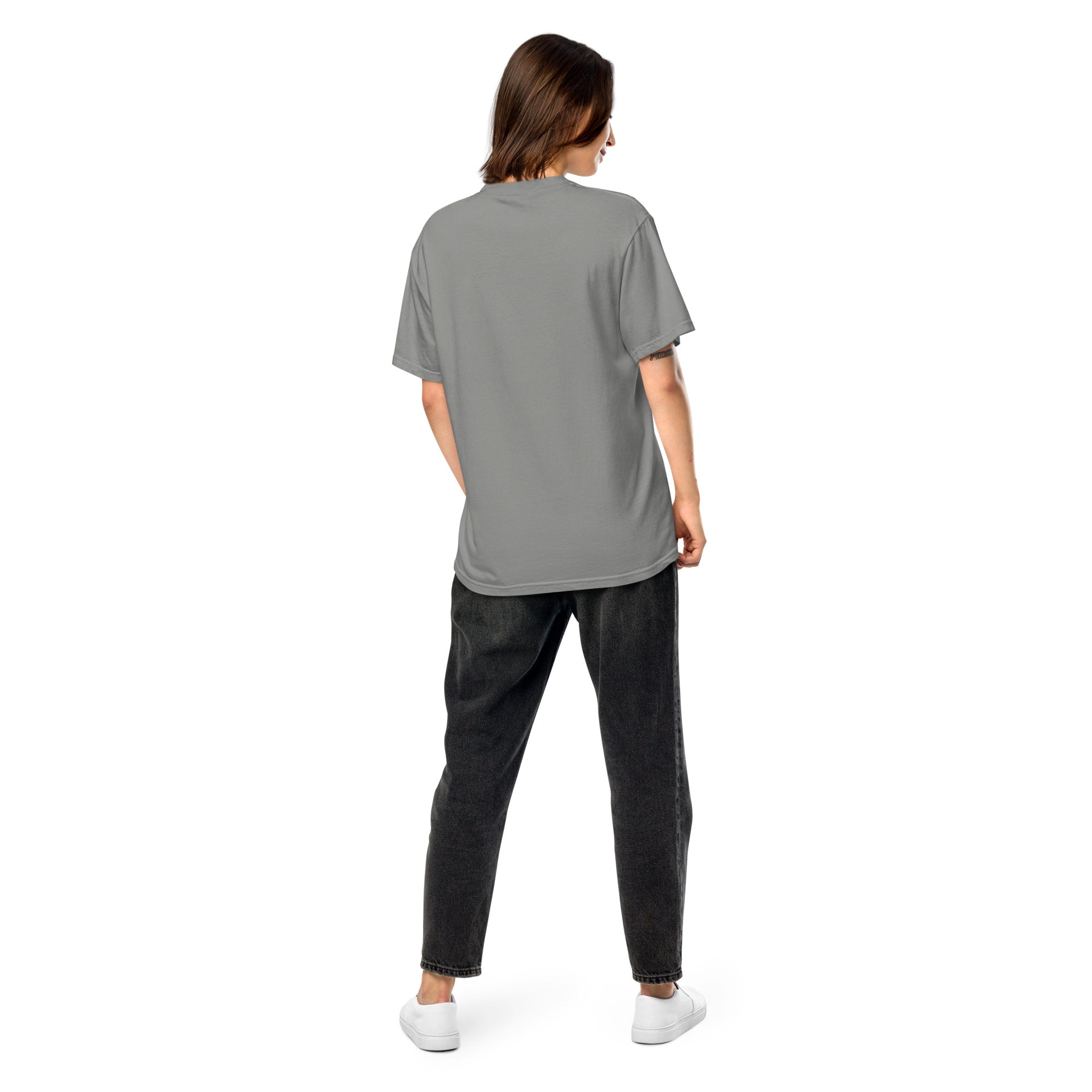 Back view of a woman wearing a Ukrainian Vibe Trizub Collection garment-dyed heavyweight t-shirt in gray, paired with black jeans and white sneakers.