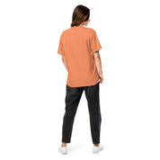 Back view of model wearing Ukrainian Vibe Trizub women’s garment-dyed heavyweight t-shirt in orange, paired with black jeans.