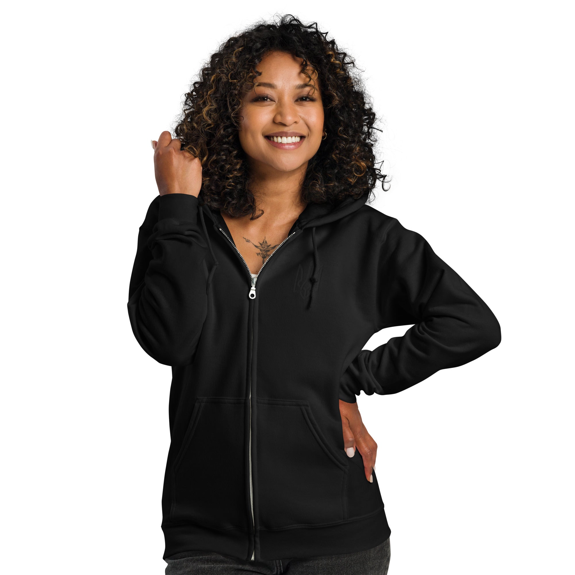Woman wearing a black heavy blend zip hoodie with Ukrainian Tryzub design, showcasing cozy style and heritage.