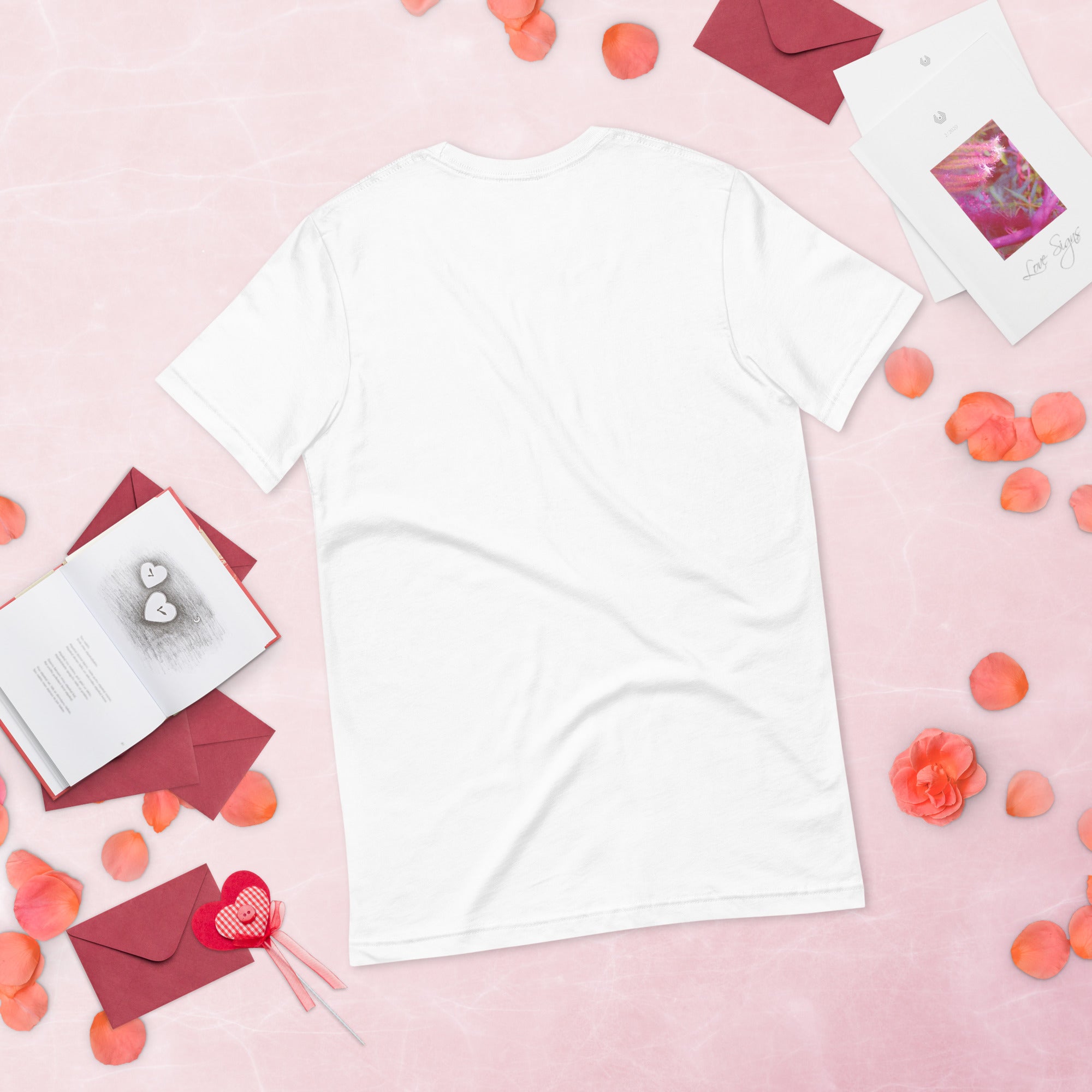 White women's T-shirt on a pink background with scattered envelopes, petals, and greeting cards