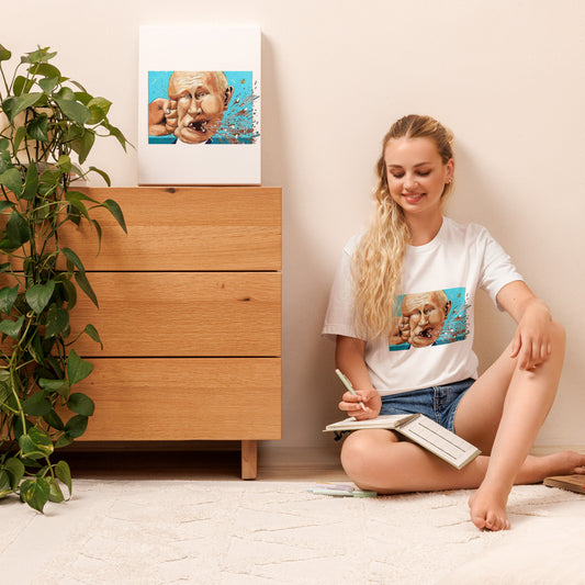 Woman wearing Stop Putin T-shirt, sitting on the floor, holding a notebook, with a related artwork on a dresser.