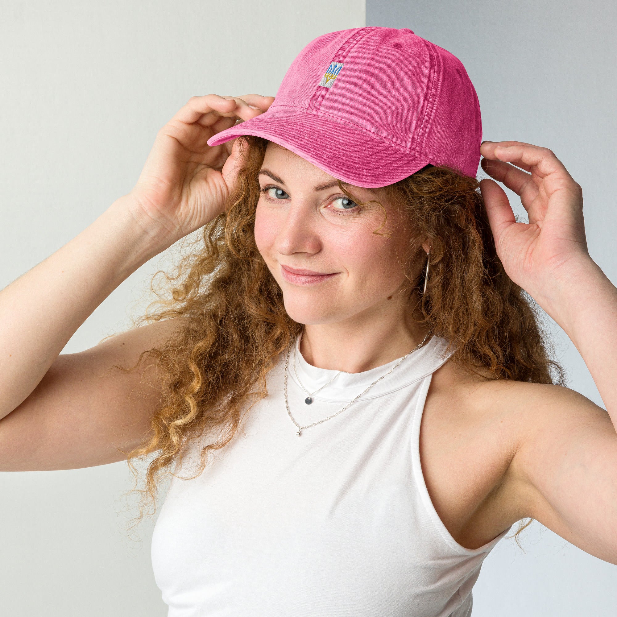 Woman wearing pink vintage cotton twill cap with Tryzub embroidery, showcasing adjustable brass buckle and washed-out design.
