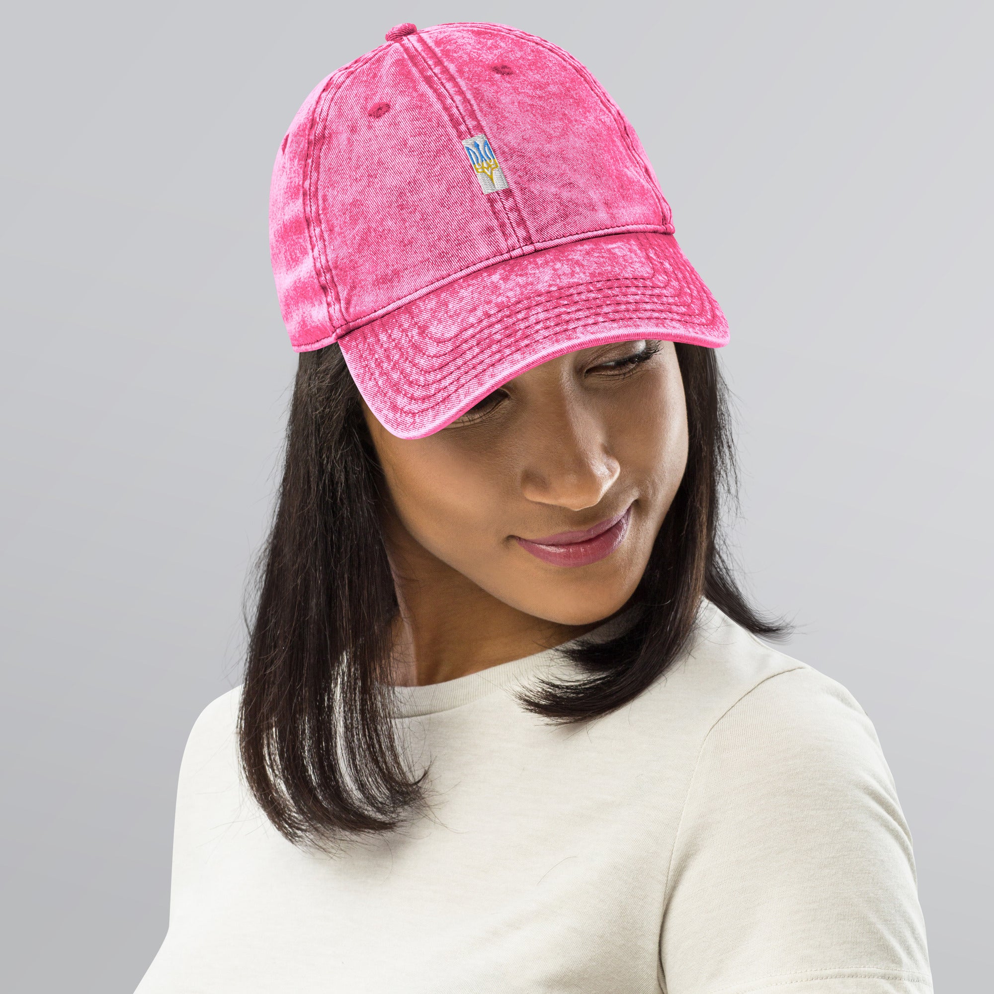 Woman wearing a pink vintage cotton twill cap with embroidered Ukrainian Tryzub, showcasing a trendy washed-out style.
