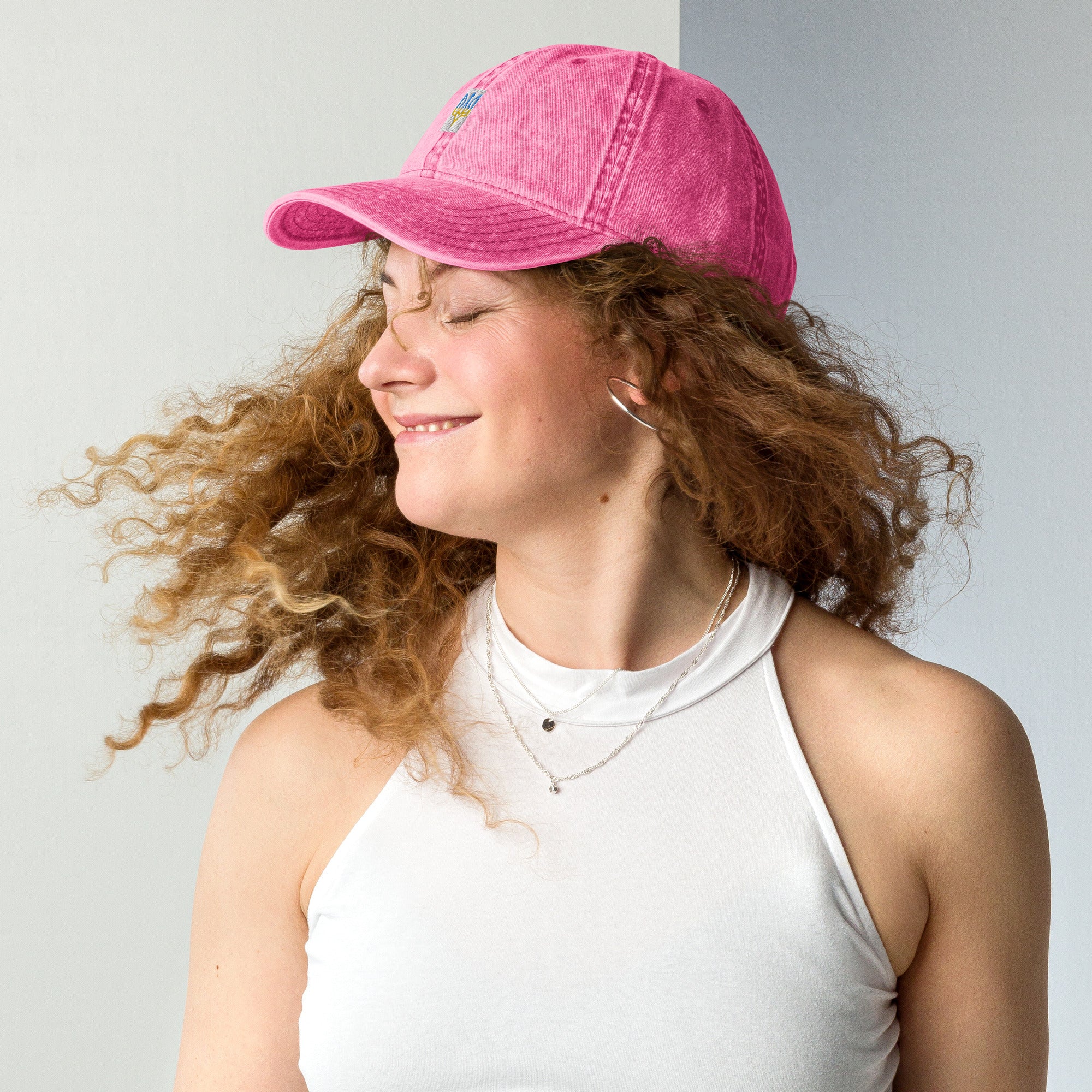 Woman wearing a vintage pink cotton twill cap with embroidered Tryzub design, showcasing a relaxed fit and stylish look.