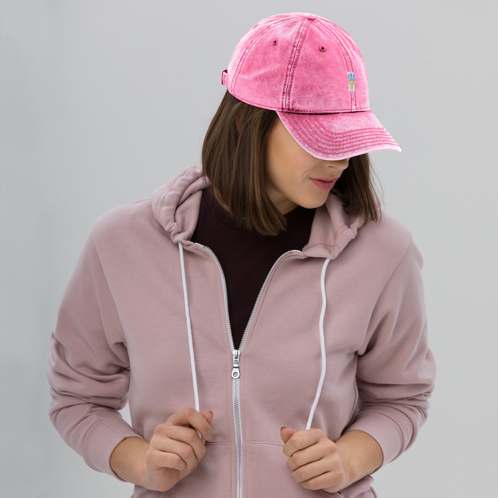 Woman wearing a pink vintage cotton twill cap with embroidered Ukrainian Tryzub, featuring a washed-out effect and adjustable fit.