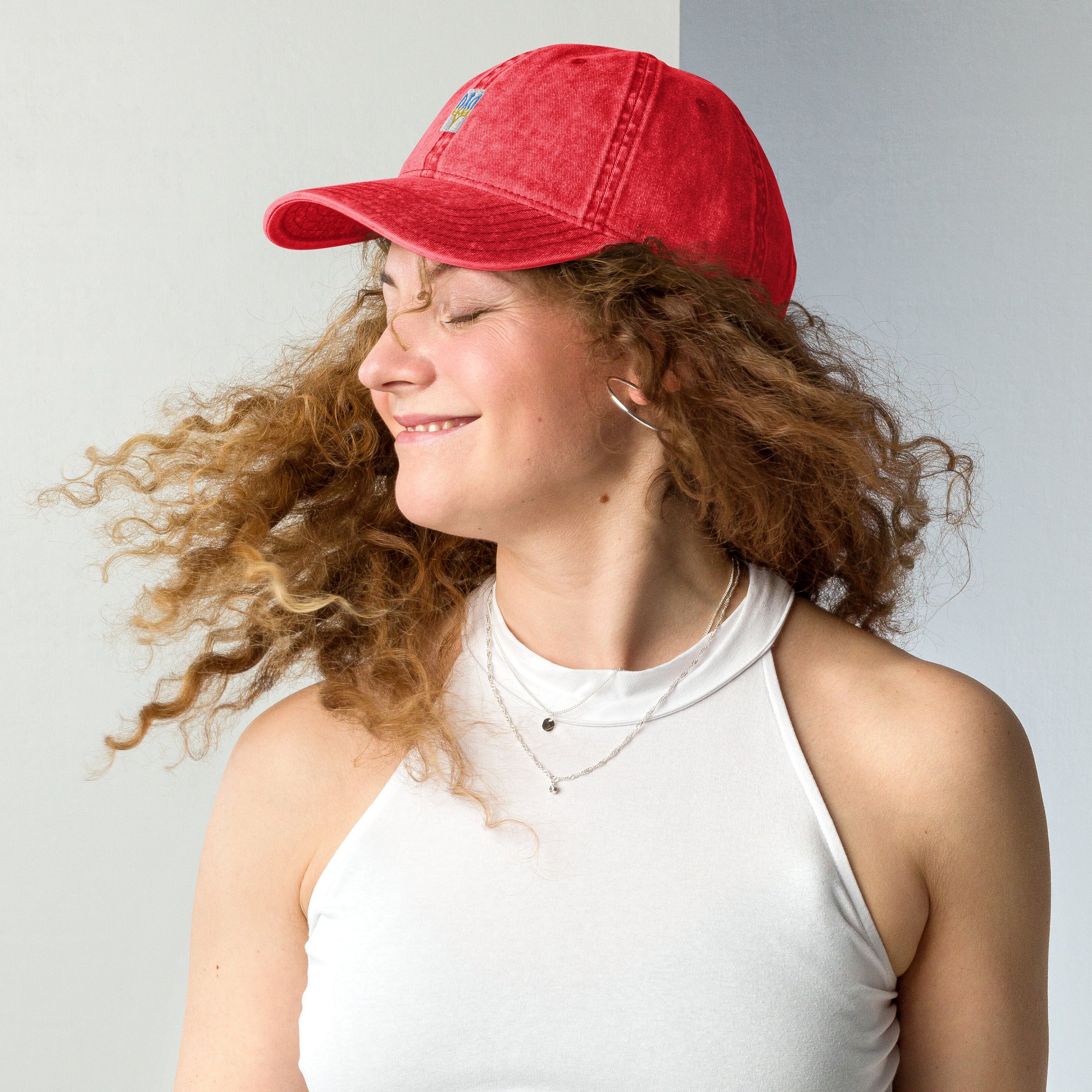 Woman wearing a red vintage unisex cotton cap with Ukrainian Tryzub embroidery, showcasing a relaxed and trendy style.