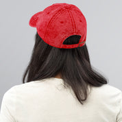 Person wearing red vintage cotton twill cap with adjustable brass buckle, showcasing back view and washed-out texture.