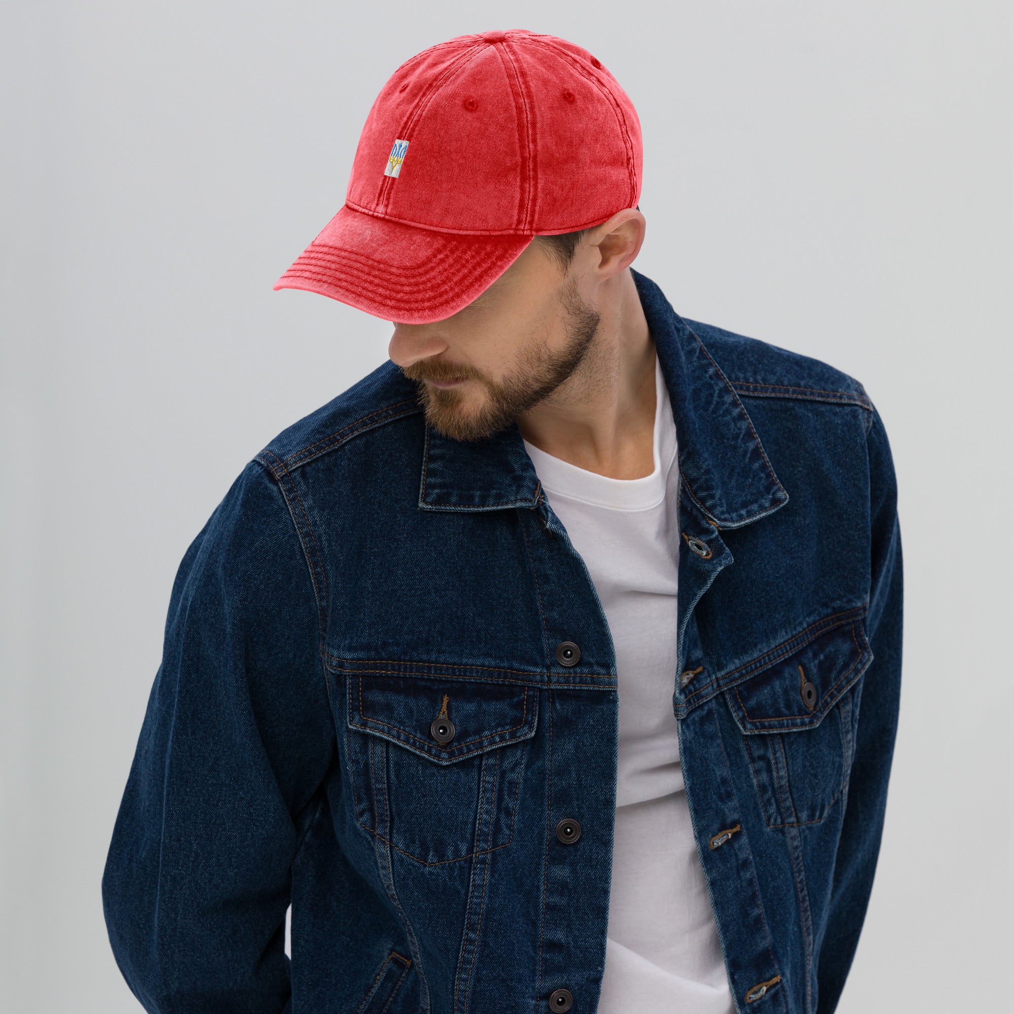 Man wearing red vintage unisex cotton twill cap with Ukrainian Tryzub embroidery, paired with a denim jacket.