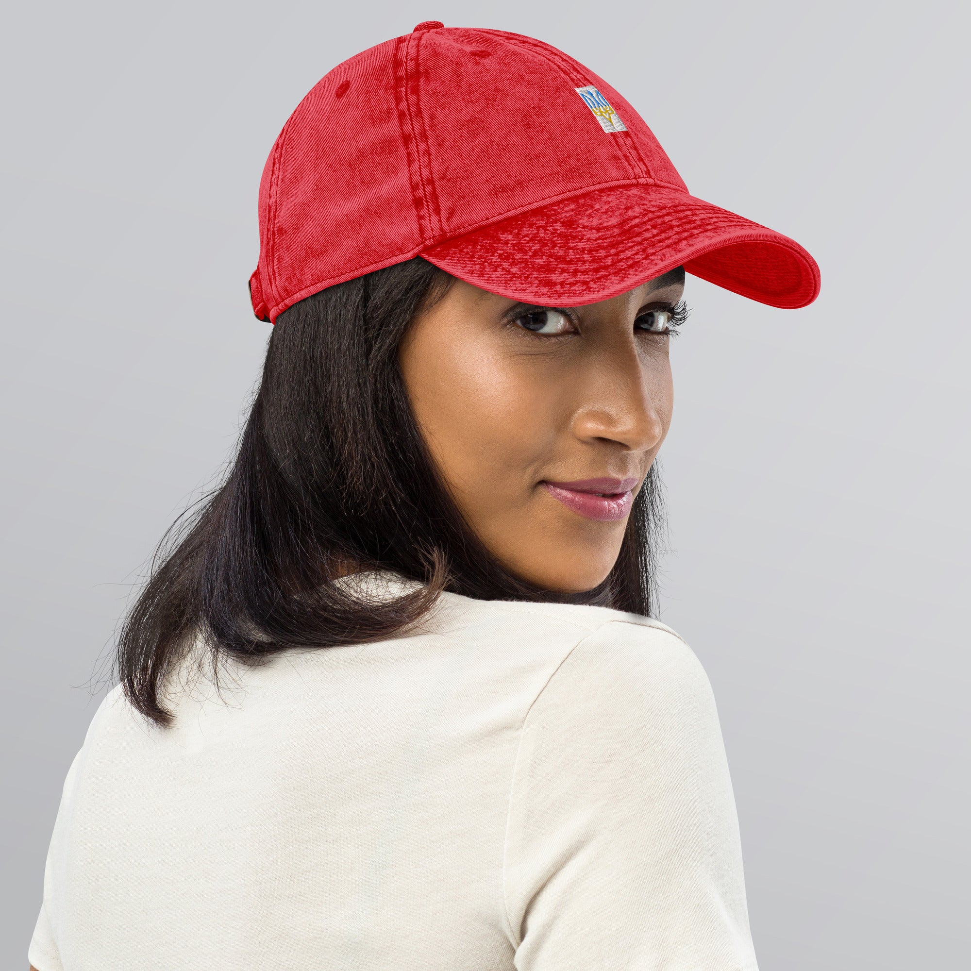 Woman wearing red vintage cotton twill cap with embroidered Ukrainian Tryzub design, showcasing fashionable and comfortable style.
