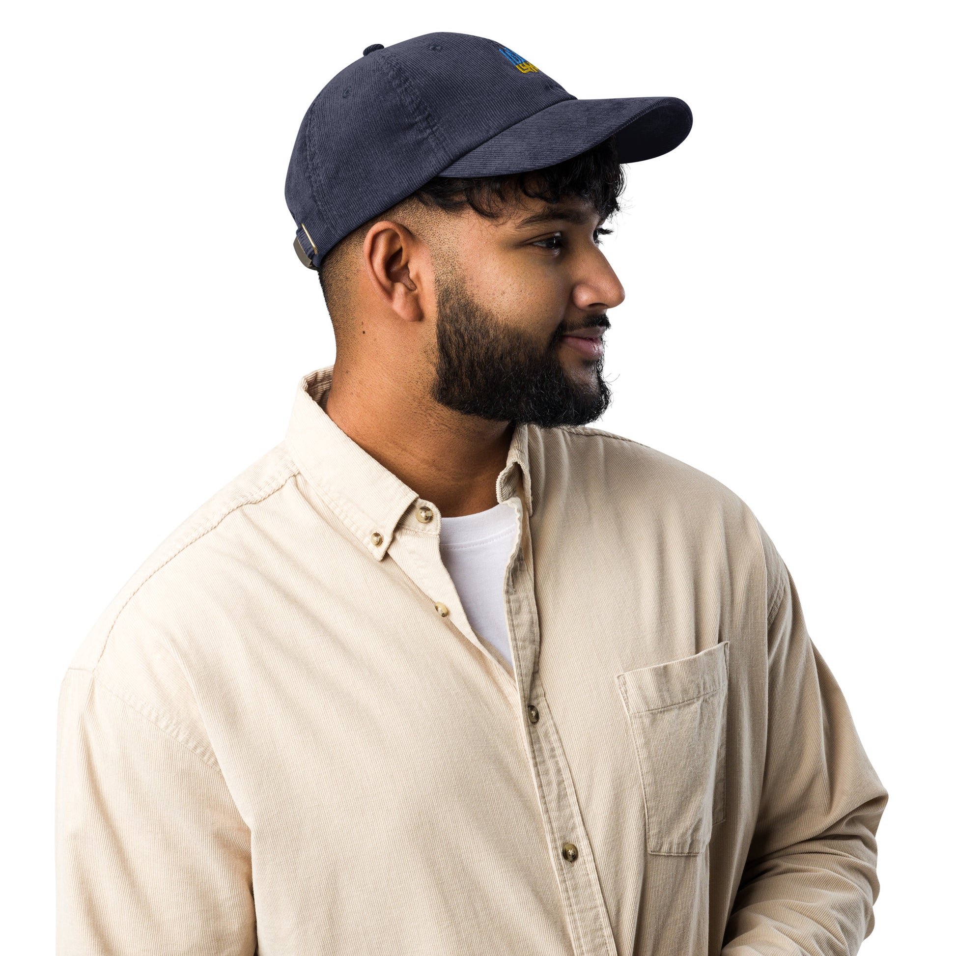Man wearing vintage corduroy cap with Ukrainian Tryzub emblem, dressed in a beige shirt, showcasing retro style and patriotic design.
