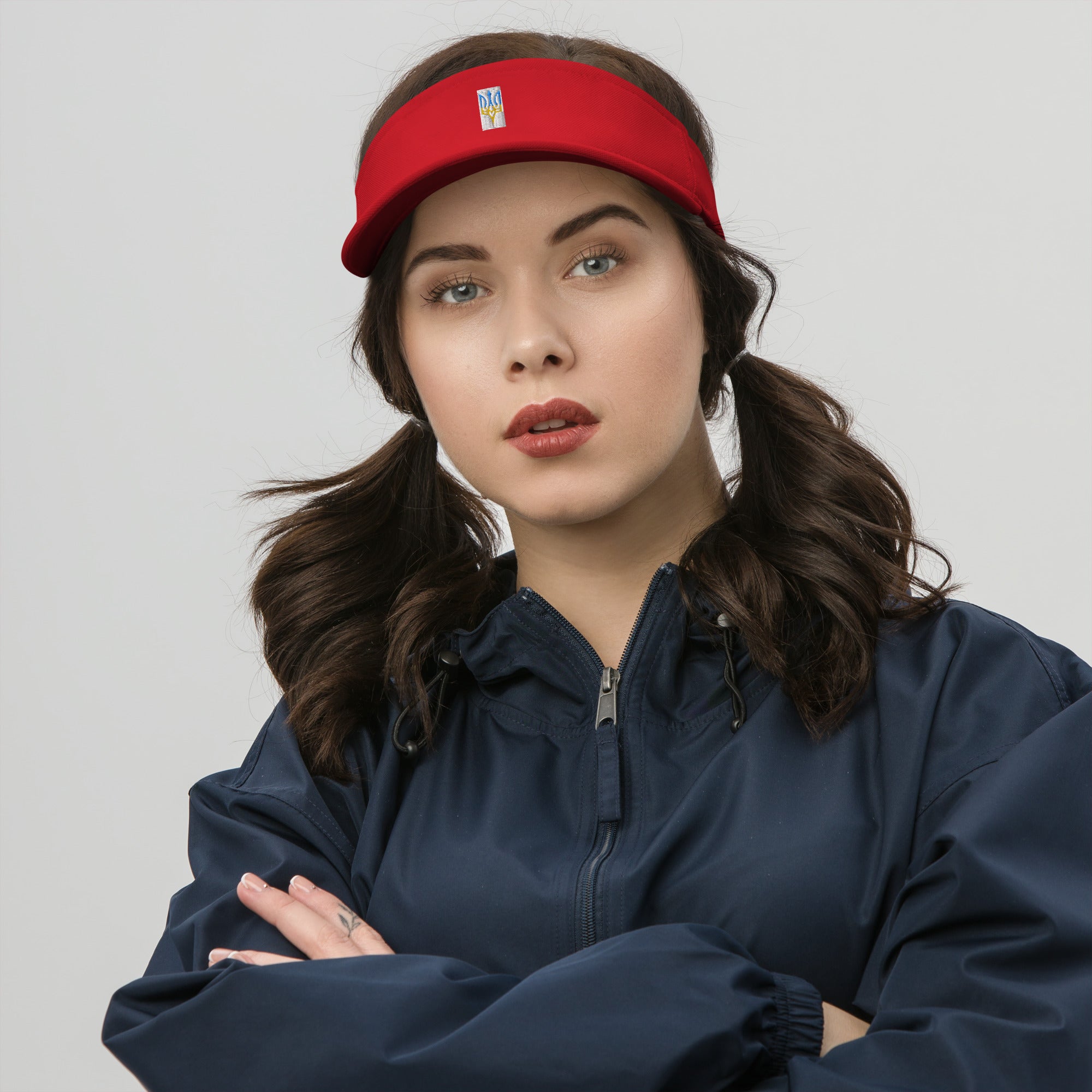 Woman wearing a red and white visor with Ukrainian Tryzub, standing against a neutral background, showcasing summer fashion.