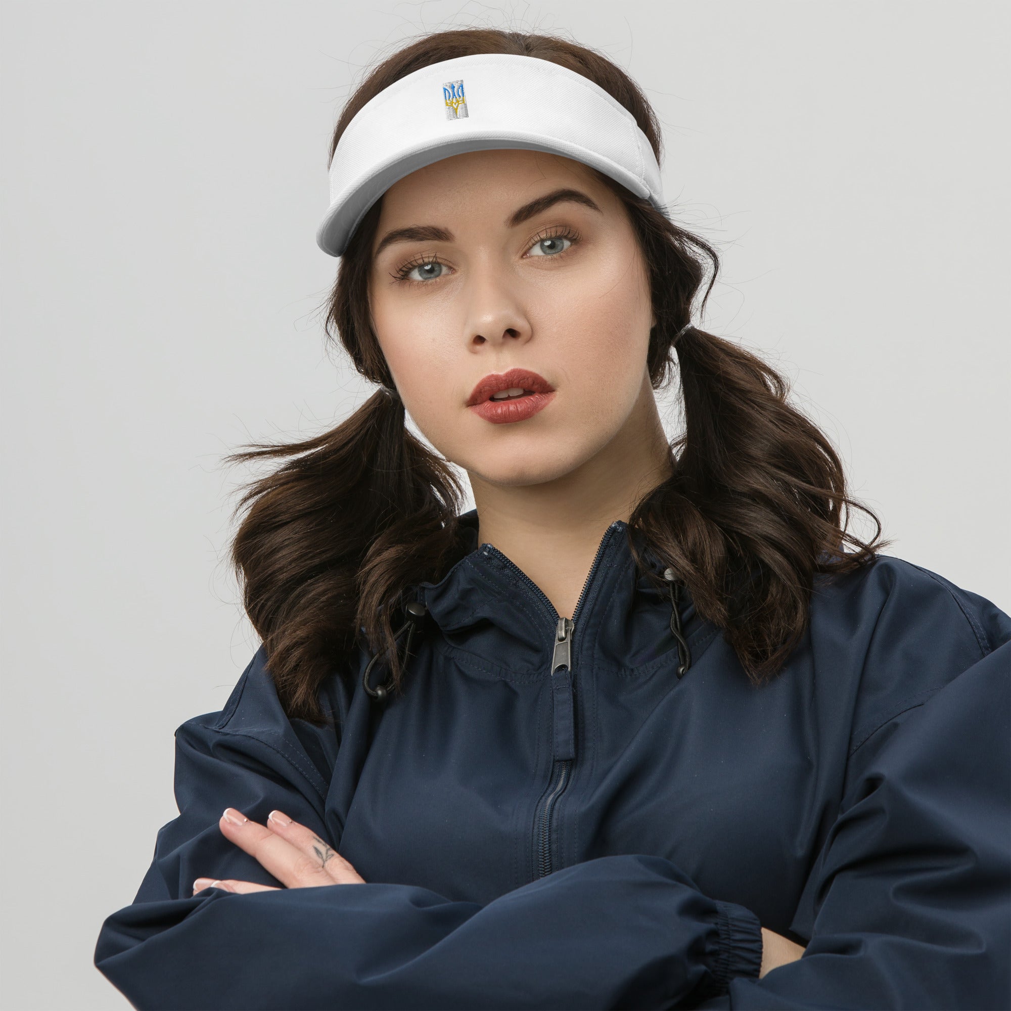 Woman wearing white visor with Ukrainian Tryzub emblem, styled with a blue jacket.