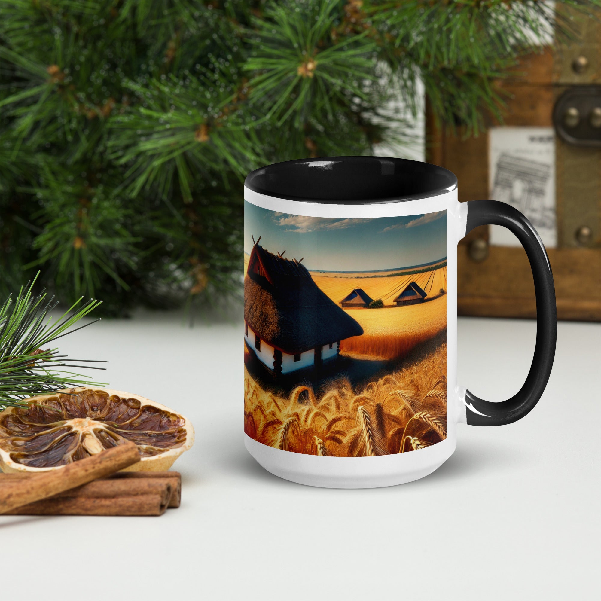 Ceramic mug with Ukrainian cottage and wheat field design, featuring a colorful rim and handle, alongside dried citrus and pine decor.