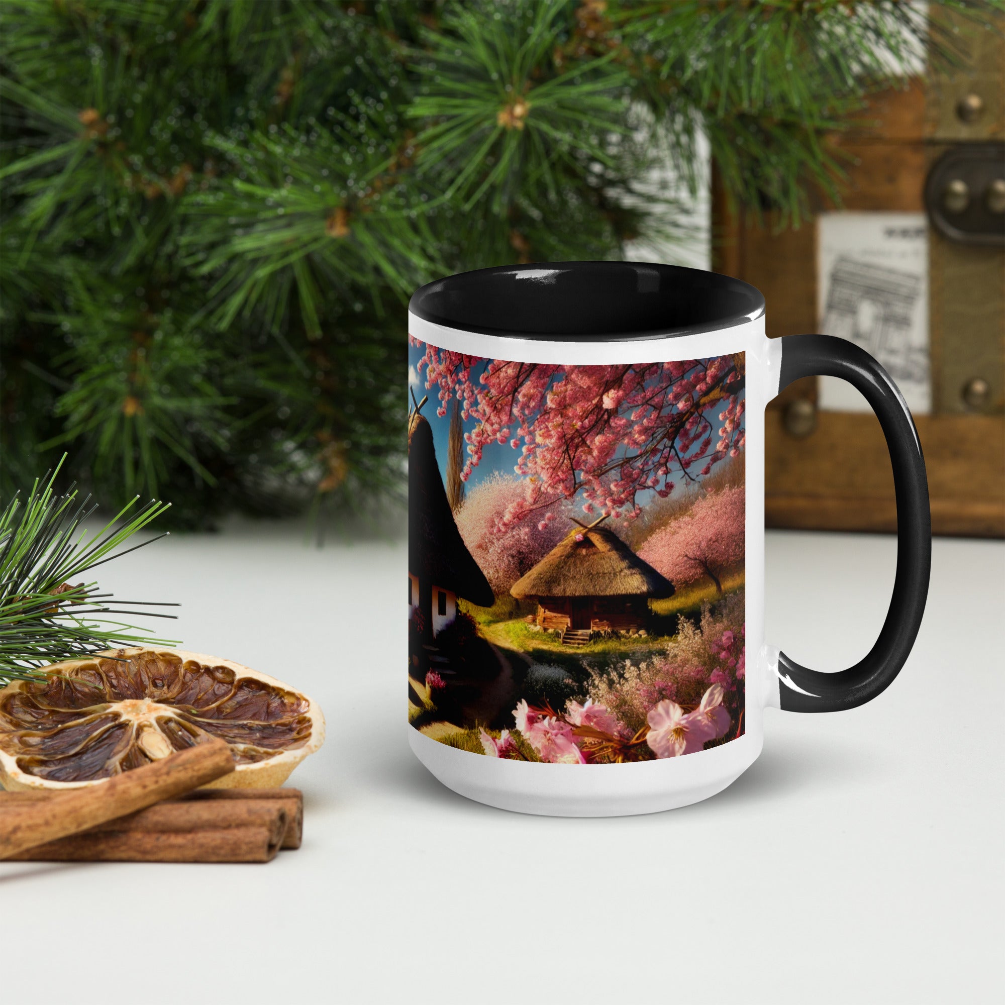 Ceramic mug with Ukrainian cottage and cherry orchard design, black rim and handle, surrounded by greenery and dried citrus.