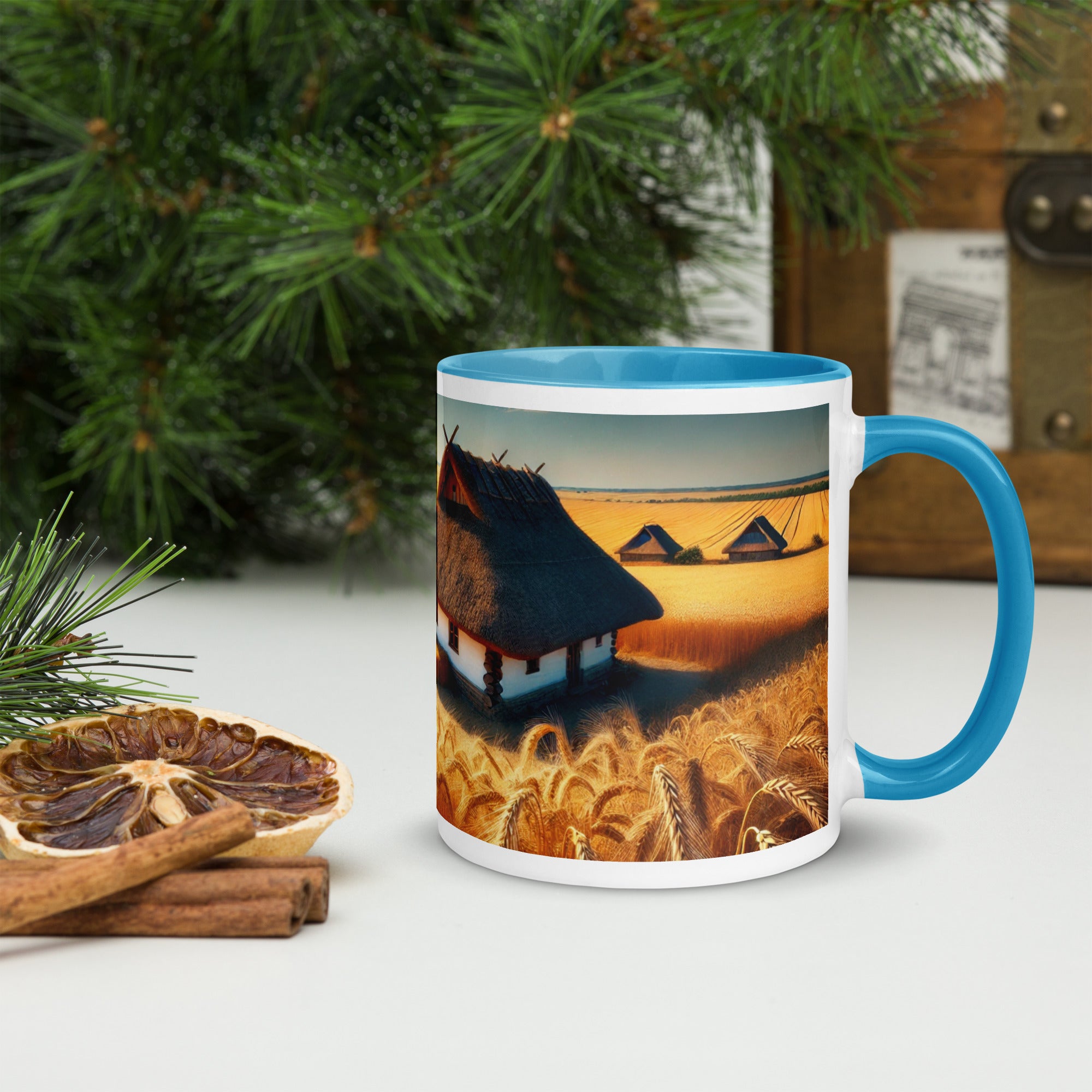 Ceramic mug with Ukrainian cottage and wheat field design, blue rim and handle, displayed on a white surface with rustic decor.