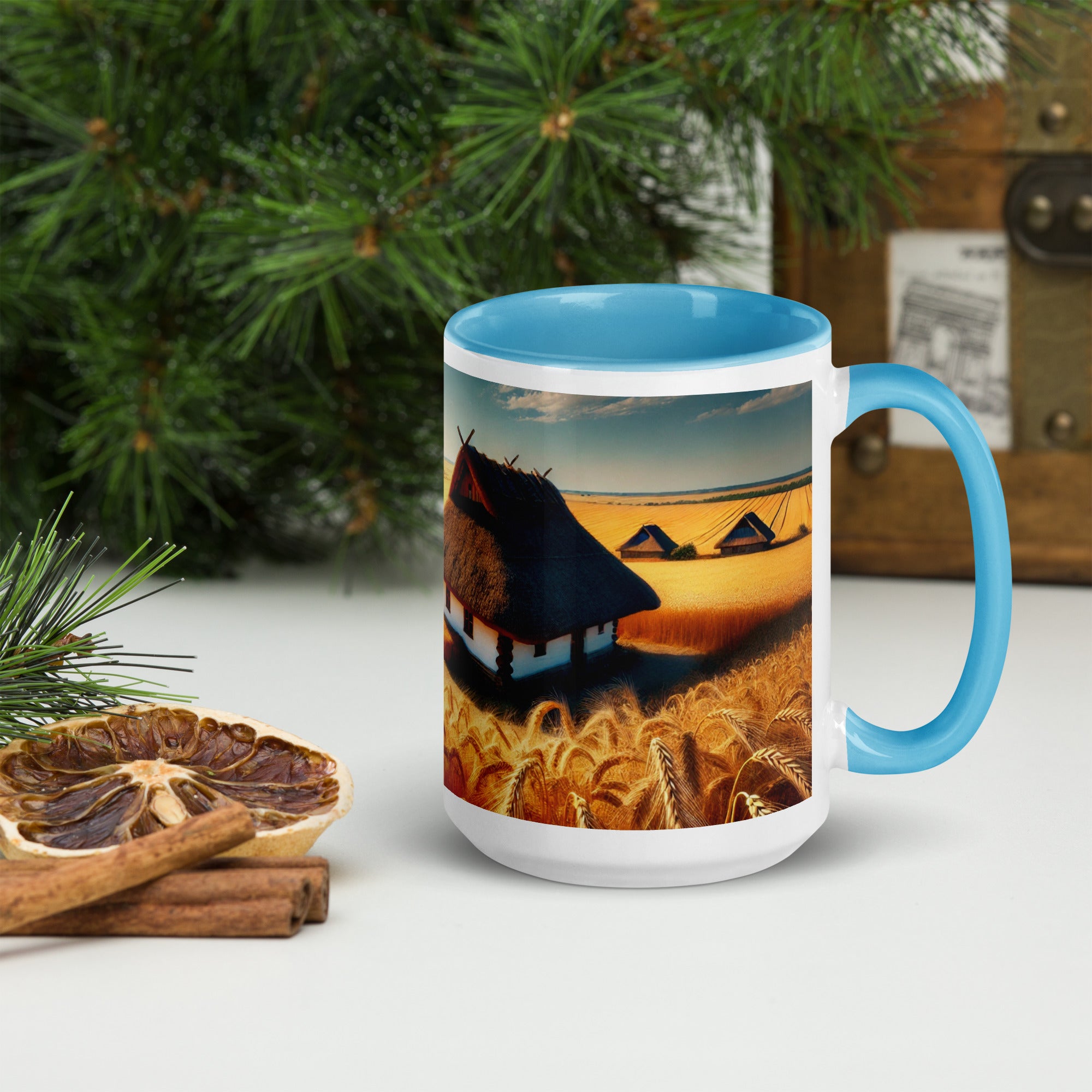 Ceramic mug with Ukrainian cottage design in wheat field, featuring a blue rim and handle, surrounded by rustic decor elements.